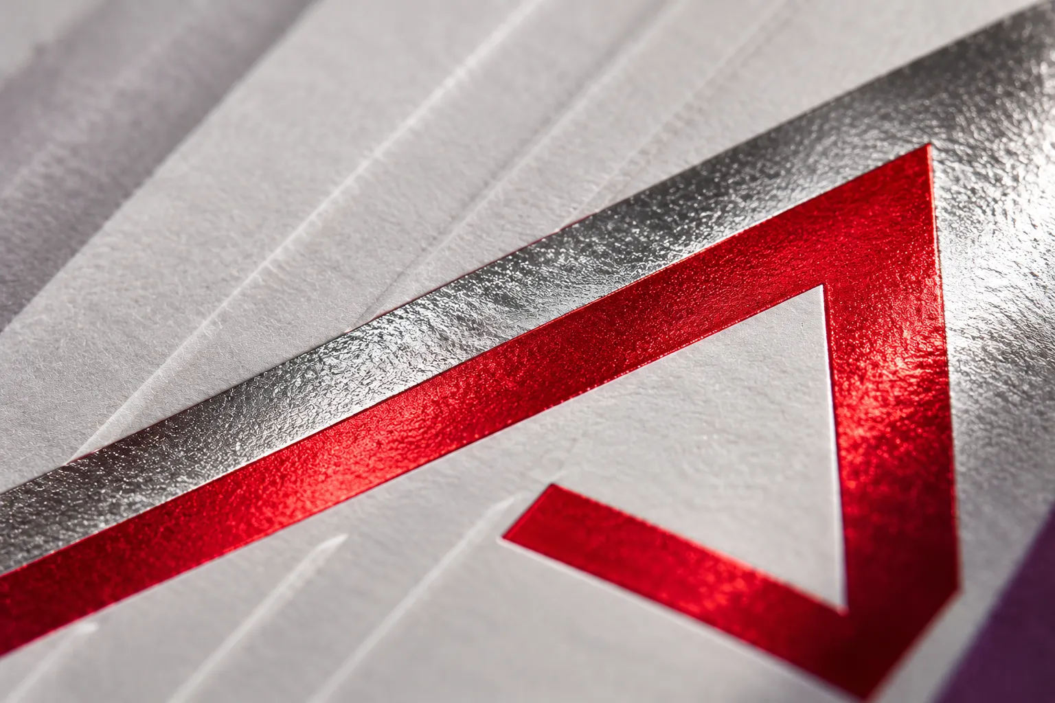 Macro d'un papier métallisé rouge se recourbant sur une feuille blanche