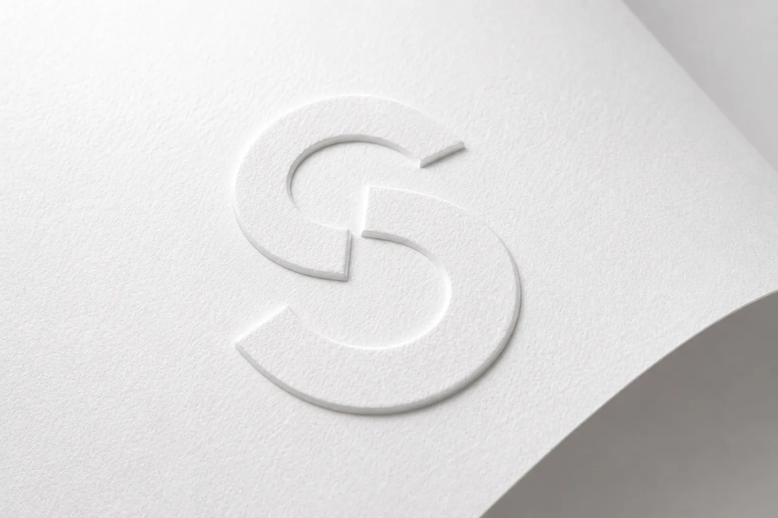 Macro d'un monogramme S gaufré en relief sur un papier blanc texturé
